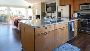 Una cocina moderna con armarios de madera, una isla grande, electrodomésticos de acero inoxidable y vistas a un balcón.