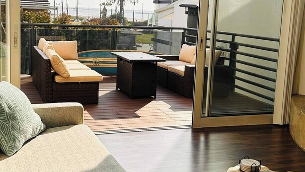 Un salón moderno con un gran ventanal corredero que da a un balcón con piscina, amueblado con sofás y una mesa de centro.