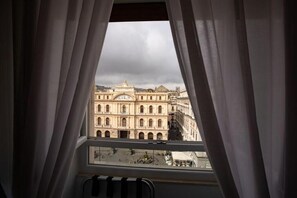 Vista desde una ventana con cortinas, con vista a un edificio histórico de arquitectura clásica.