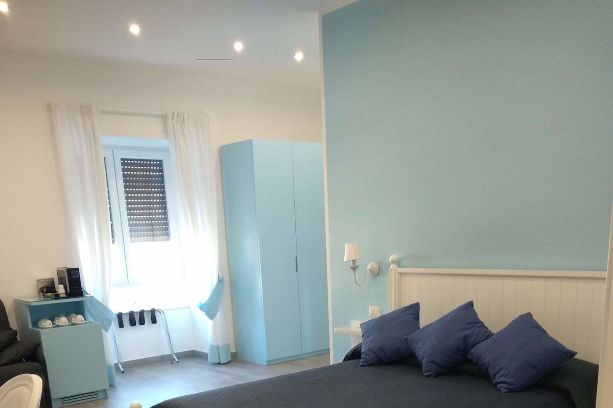 A bedroom with a large bed, a wardrobe, a desk, and a chair.