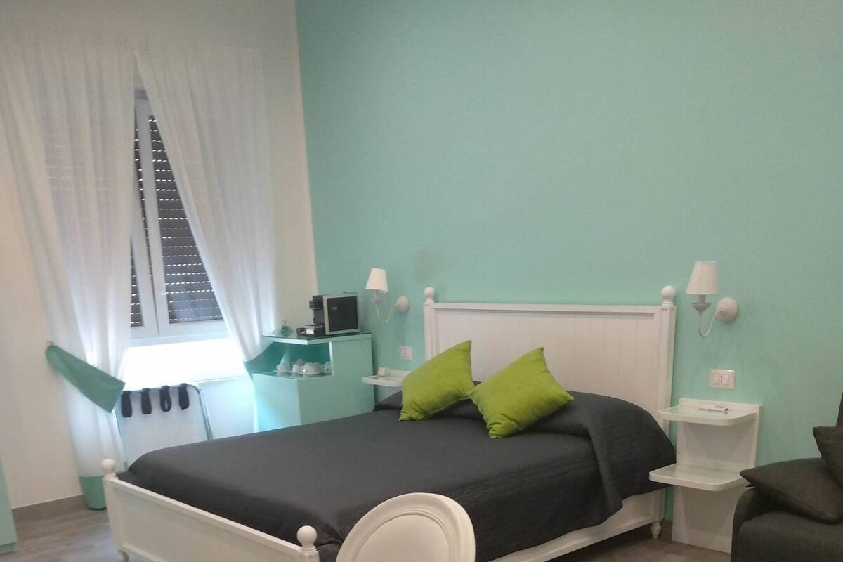 A bedroom with a bed, a chair, a desk, and a small table.
