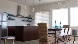 A modern kitchen with dark wood cabinetry, a central island, and white chairs.