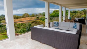 A balcony with a wicker sofa, a dining table, and chairs.