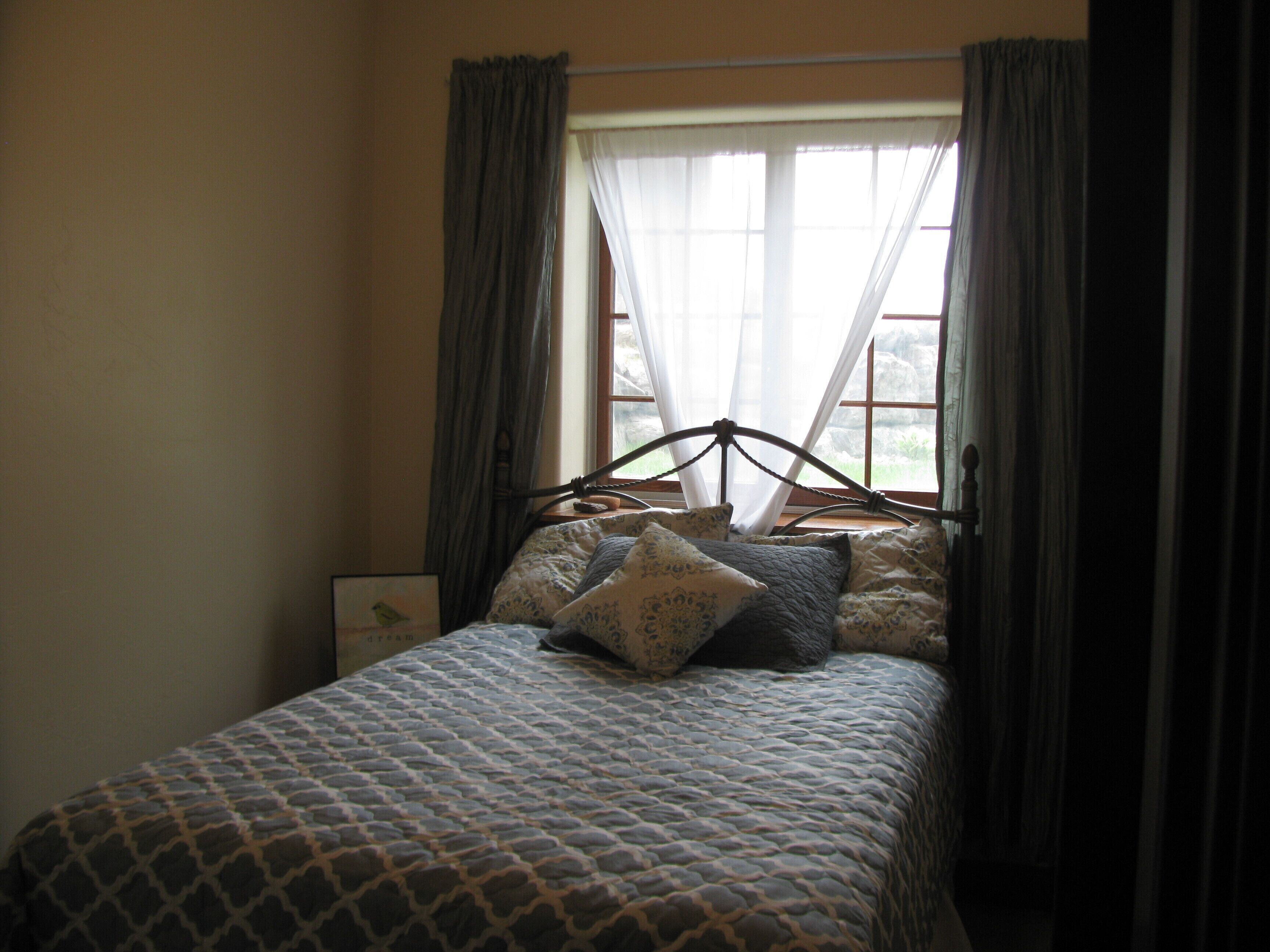 A bed with a patterned bedspread, a headboard, and two pillows.