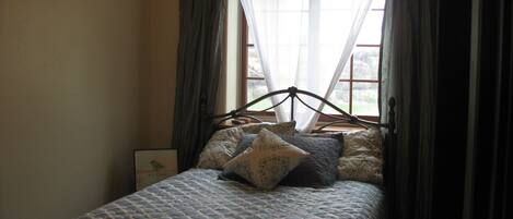 A bed with a patterned bedspread, a headboard, and two pillows.