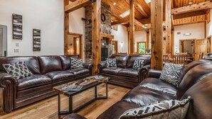 A spacious living room with leather sofas, a coffee table, and wooden beams. - 200-Acre Group & Reunion Lodge near Cook Forest — PA WILDS, Sleeps 18 (Shippenville)