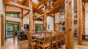 A spacious dining area with wooden tables and chairs, a fireplace, and large windows offering views of the outdoors. - 200-Acre Group & Reunion Lodge near Cook Forest — PA WILDS, Sleeps 18 (Shippenville)