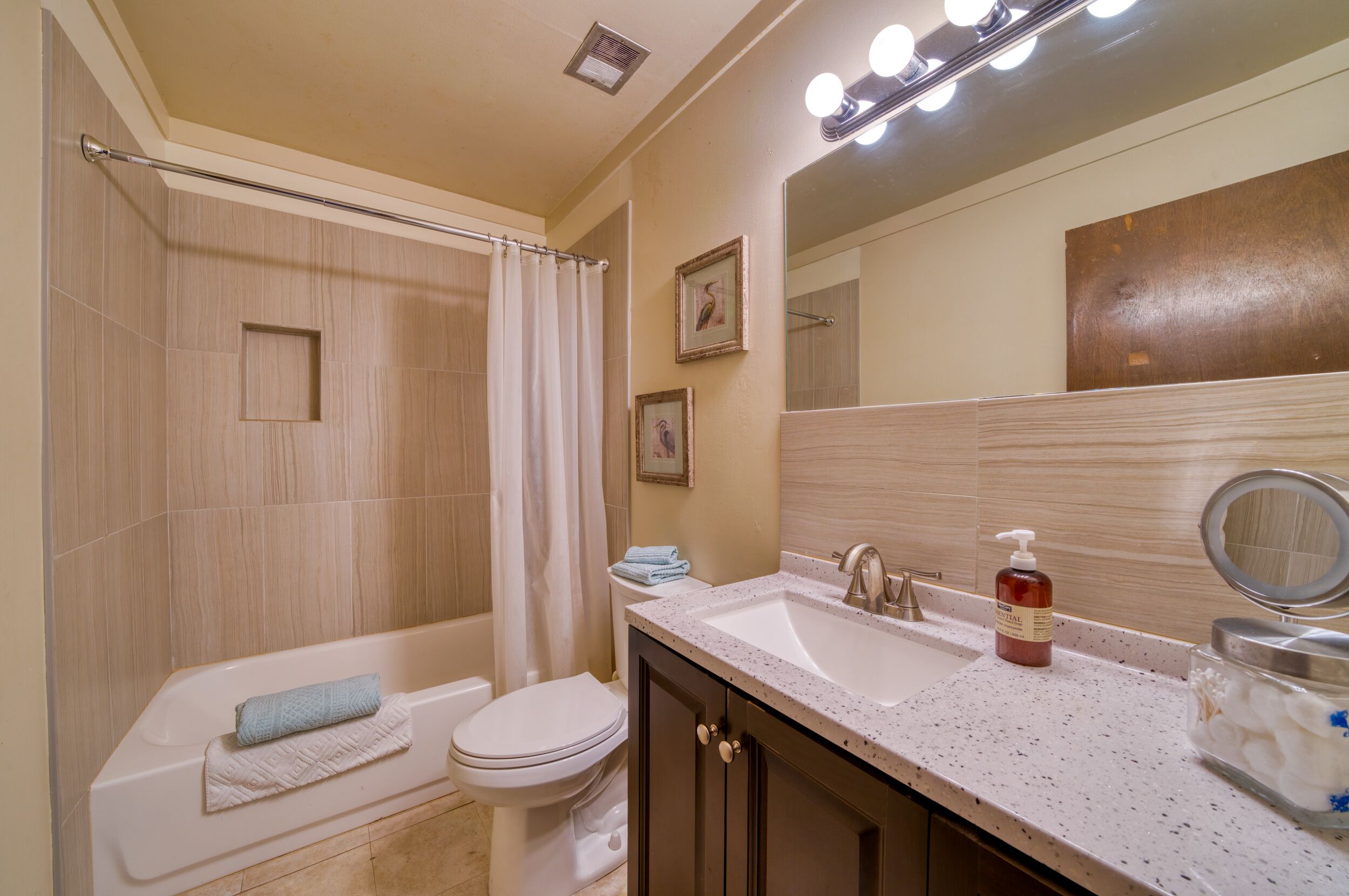 A bathroom with a bathtub, toilet, sink, and a mirror.
