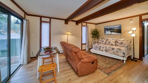 A living room with a sofa, a dining table with chairs, a lamp, and a painting on the wall.