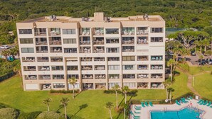 Un hotel amb diversos pisos, balcons, una piscina i un paisatge verd abundant.