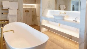 A modern bathroom with a freestanding bathtub, a large mirror, and a vanity with a sink.