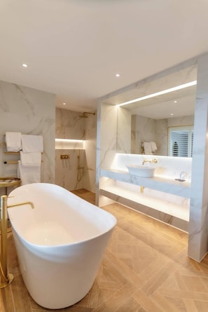 A modern bathroom with a freestanding bathtub, a large mirror, and a vanity with a sink.