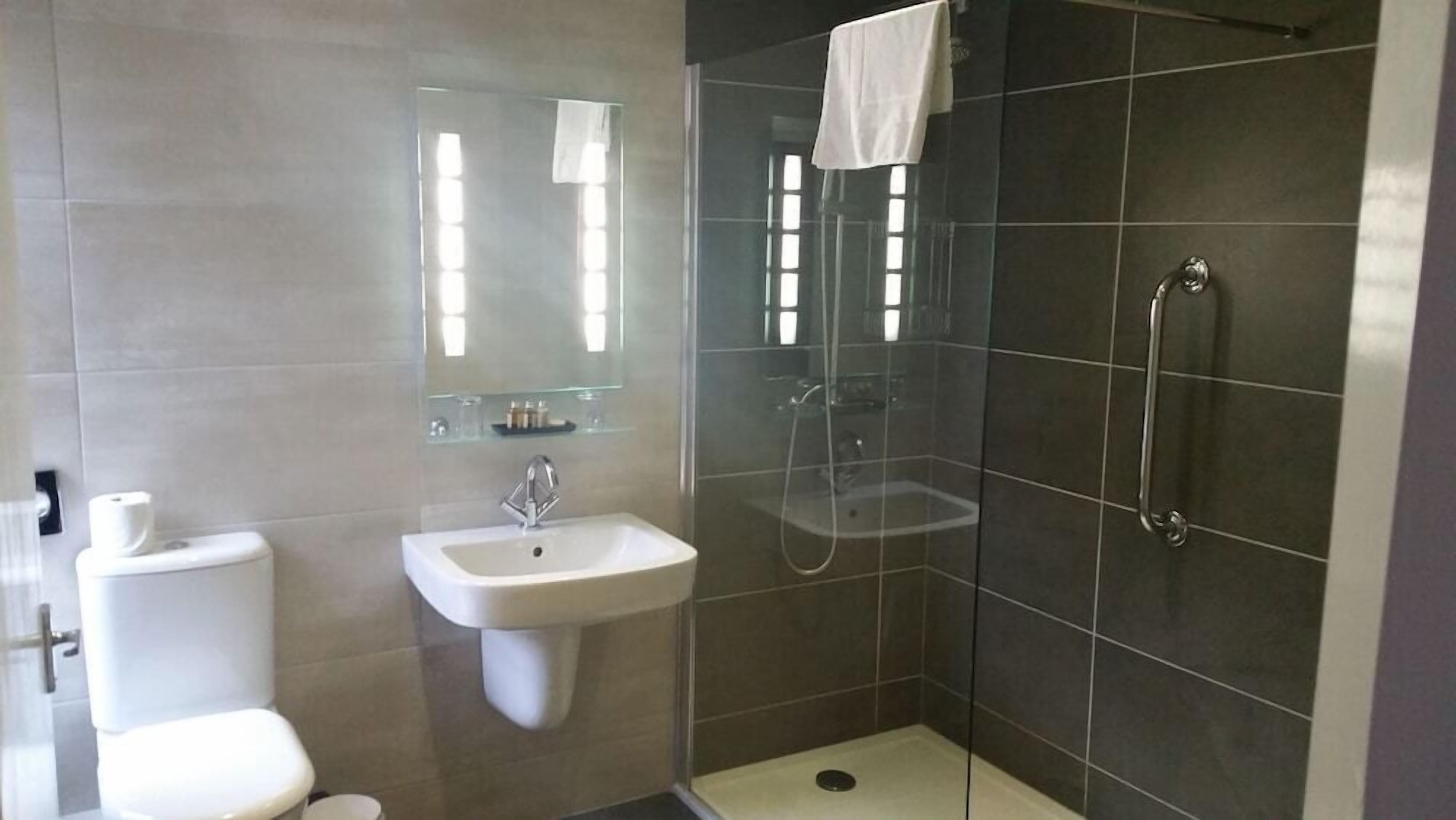 A modern bathroom with a toilet, sink, and glass-enclosed shower.