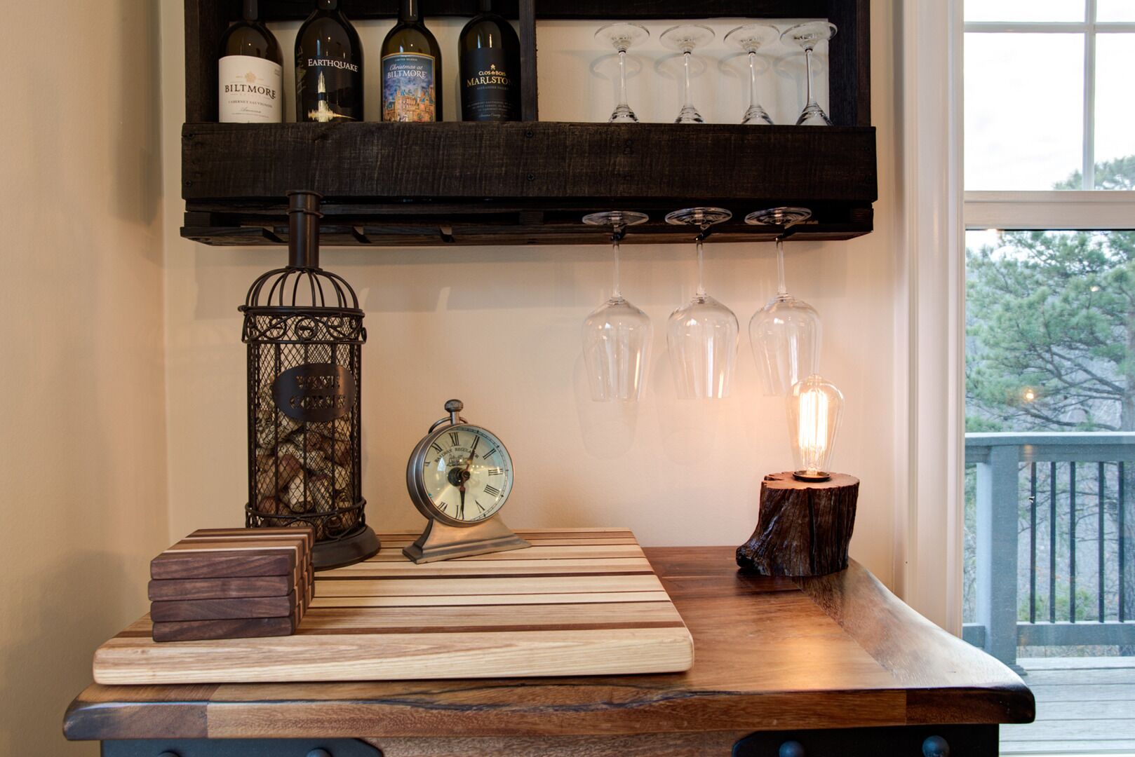 Une table en bois, sur laquelle se trouvent une horloge, une bougie et une bouteille de vin, posées sur une étagère au-dessus.