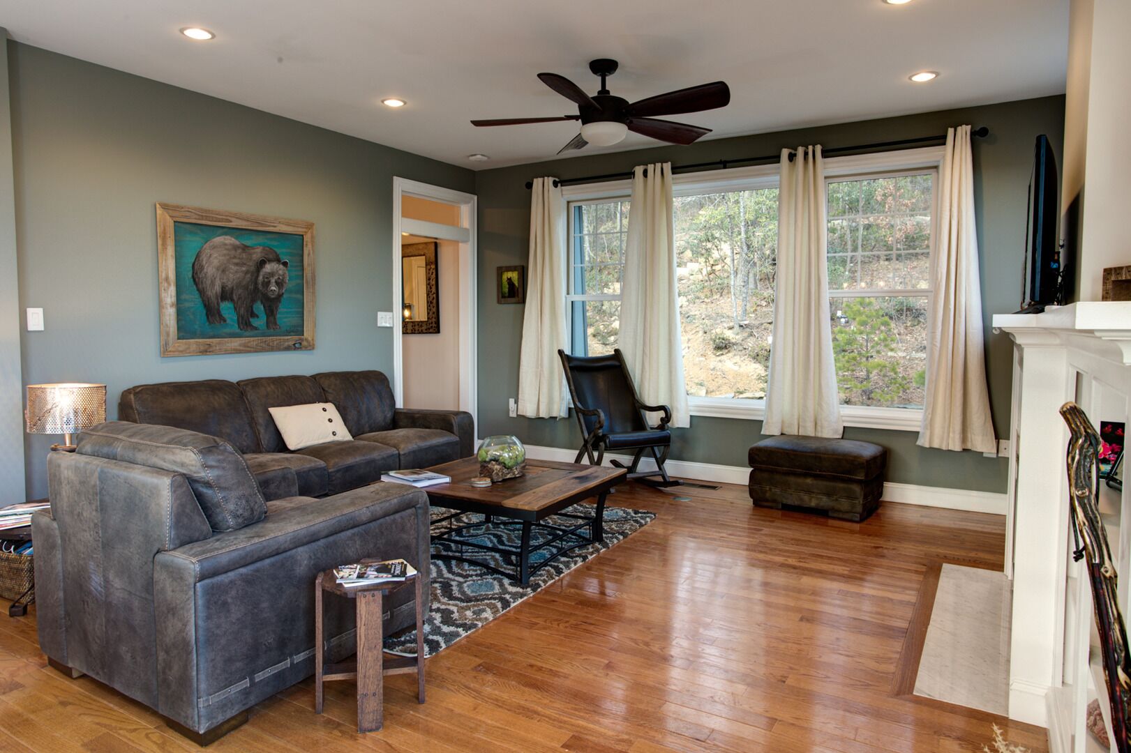 A living room with a grey sofa, a black rocking chair, a wooden coffee table, and a fireplace.