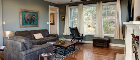 A living room with a grey sofa, a black rocking chair, a wooden coffee table, and a fireplace.