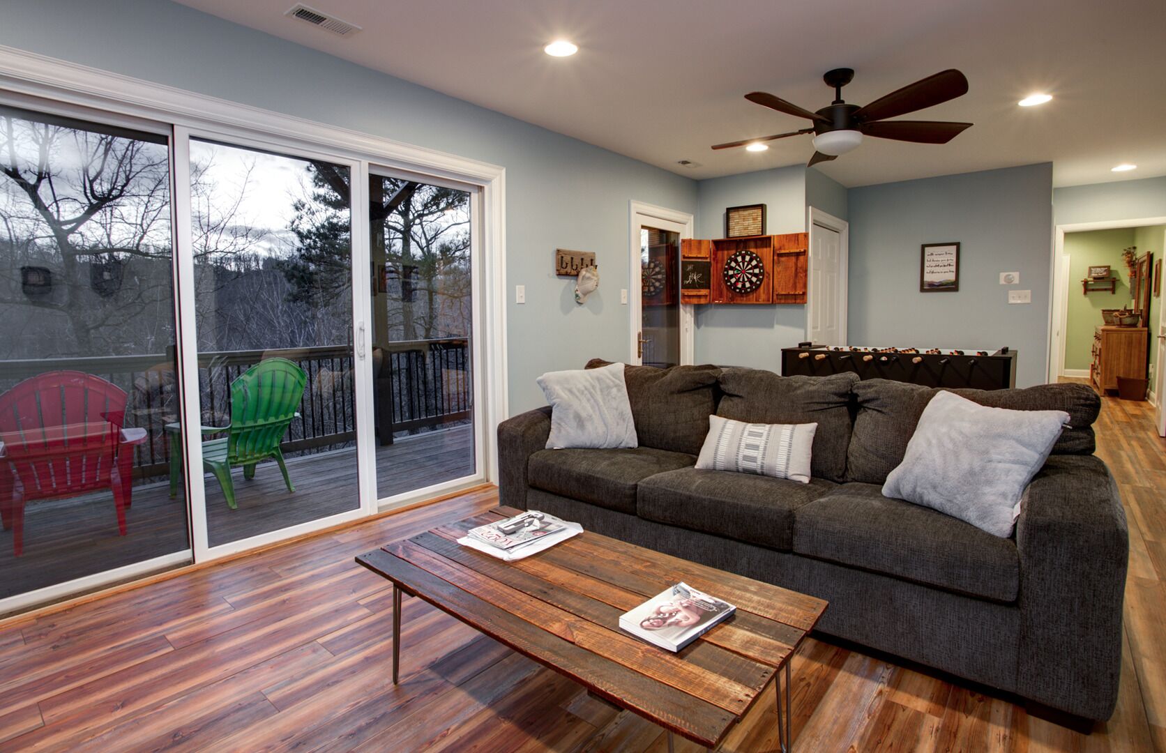 A living room with a grey sofa, wooden coffee table, and a ceiling fan.