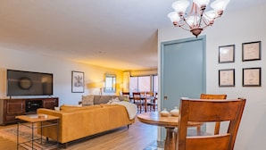 Una sala de estar con sofá, televisor y mesa de comedor.