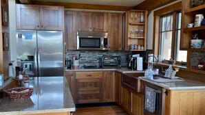 Una cucina moderna con mobili in legno, elettrodomestici in acciaio inossidabile e un'ampia finestra che permette luce naturale.