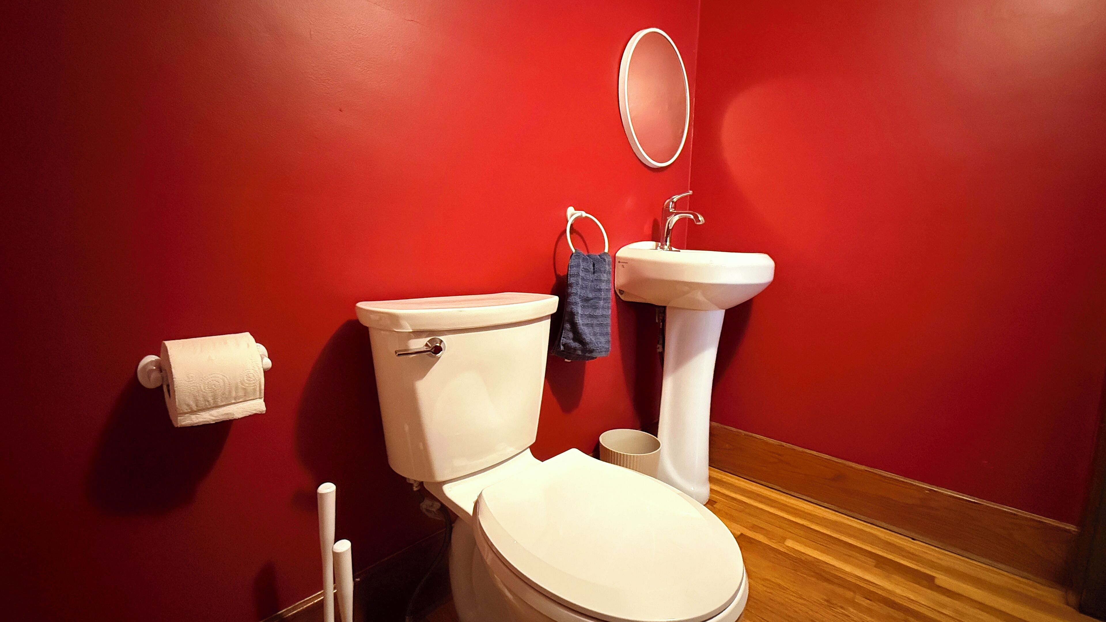 A bathroom with a toilet, sink, and mirror.