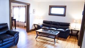 A living room with a black leather sofa, a coffee table, and two lamps on side tables.