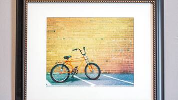En inramad bild som föreställer en cykel som står lutad mot en tegelvägg.