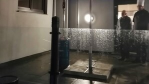 An outdoor area with a metal umbrella structure, a tiled floor, and a wall with a circular design. - Hotel Langstedt (Langstedt)