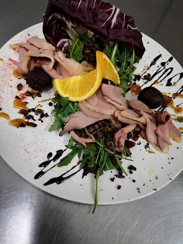A plate of food with various meats, greens, and a lemon slice. - Hotel Langstedt (Langstedt)