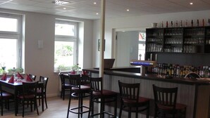 A restaurant with a bar area, wooden chairs, and a dining table. - Hotel Langstedt (Langstedt)