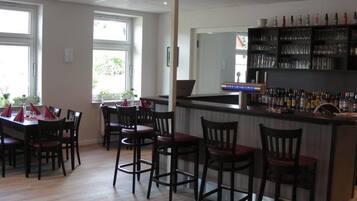 Un restaurante con una zona de bar, sillas de madera y una mesa de comedor.