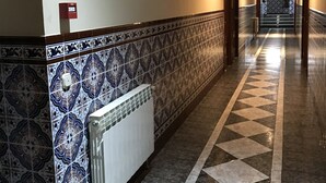 A hallway with patterned tiles, a radiator, and a framed certificate on the wall. - Santa Ana Hostal (Madridejos)
