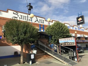 A building with a sign reading "Santa Ana" and a "Visit Nuestra Tenda Museo" sign. - Santa Ana Hostal (Madridejos)