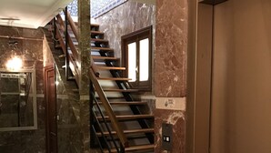 A staircase with marble walls and a checkered floor. - Santa Ana Hostal (Madridejos)