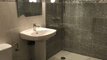 Un baño con lavamanos, espejo y ducha.