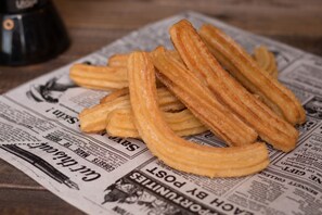 A stack of churros on a newspaper. - Santa Ana Hostal (Madridejos)
