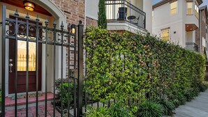 A residential building with a brick facade, a gated entrance, and a well-maintained hedge.