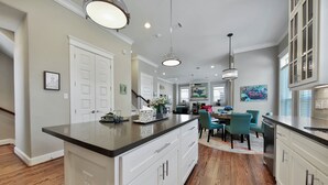 A spacious kitchen with a large island, white cabinetry, and pendant lighting.