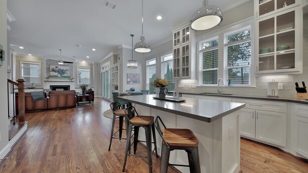 A spacious kitchen with a large island, bar stools, and a dining area with a sofa and chairs.