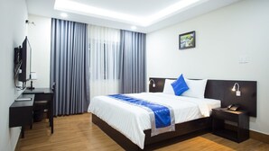 A modern hotel room with a large bed, a desk, a chair, a TV, and a picture on the wall. - SoLex Hotel (Ho Chi Minh City)
