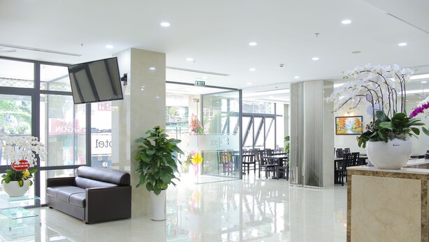 A modern lobby with a leather sofa, glass partitions, and potted plants. - SoLex Hotel (Ho Chi Minh City)