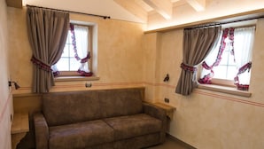 Una habitación con sofá, dos ventanas con cortinas y una lámpara.
