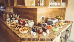 Una mesa de madera con una variedad de alimentos, salsas y bebidas dispuestas en un bufé.