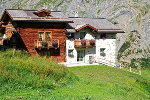 A rustic chalet with a wooden facade, balconies with flower boxes, and a mountain backdrop. - Al Solif Bed & Breakfast (Livigno)
