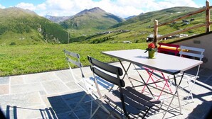 Un patio al aire libre con una mesa y sillas, con vista a un paisaje montañoso.