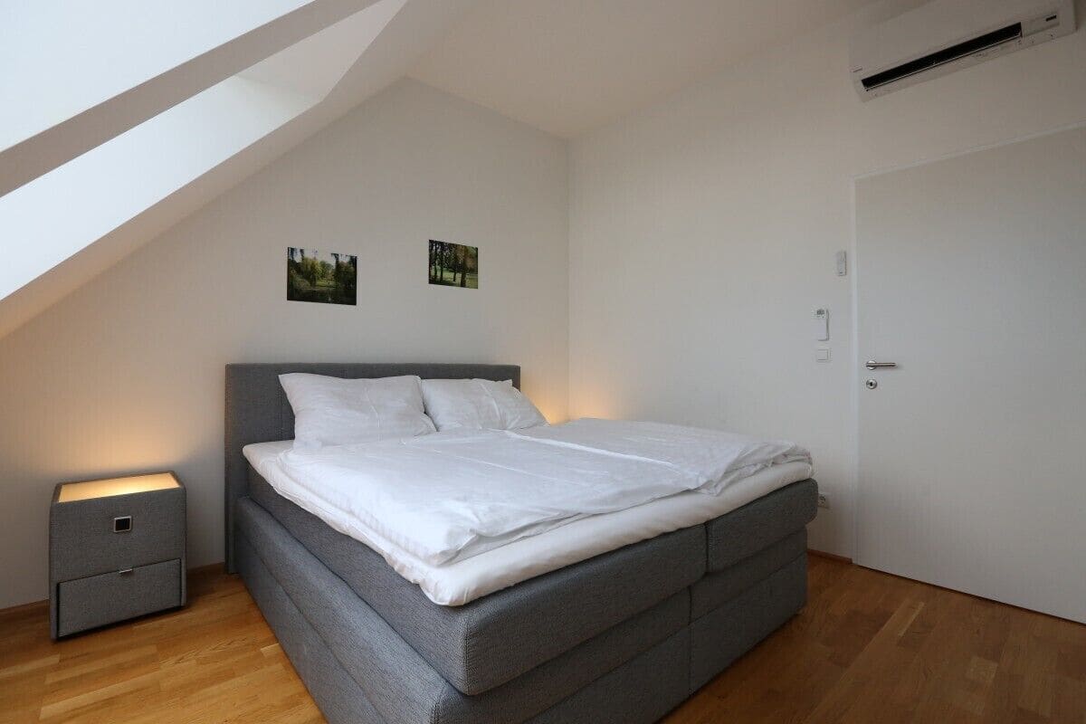 A bedroom with a bed, a nightstand, and a door.
