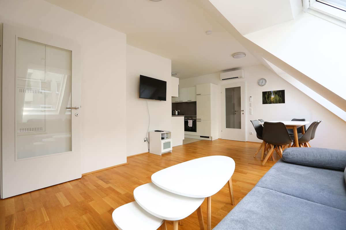 A modern living space with a dining area, kitchen, and a staircase leading to an upper level.