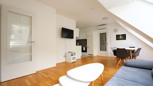 Un espacio de estar moderno con comedor, cocina y una escalera que lleva a un nivel superior.