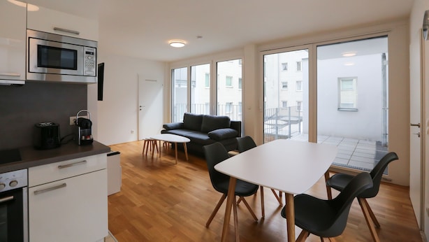 Una cocina moderna con microondas, cafetera y comedor con mesa y sillas.