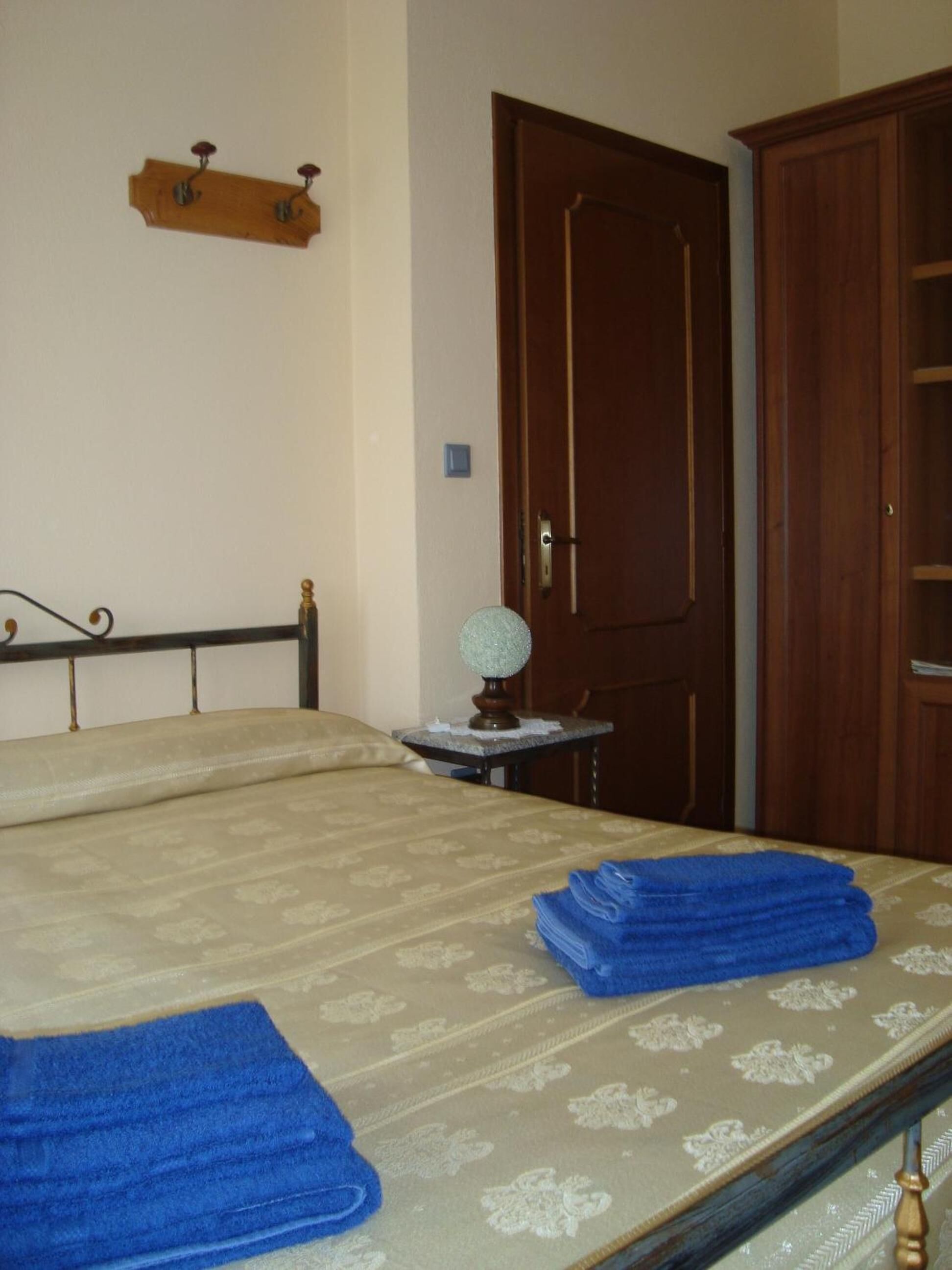 Une chambre à coucher avec un lit, une porte en bois, une petite table avec une lampe et un porte-manteau.