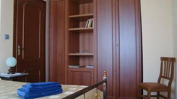 Un dormitorio con cama, armario de madera, una silla y una mesita con un globo terráqueo.